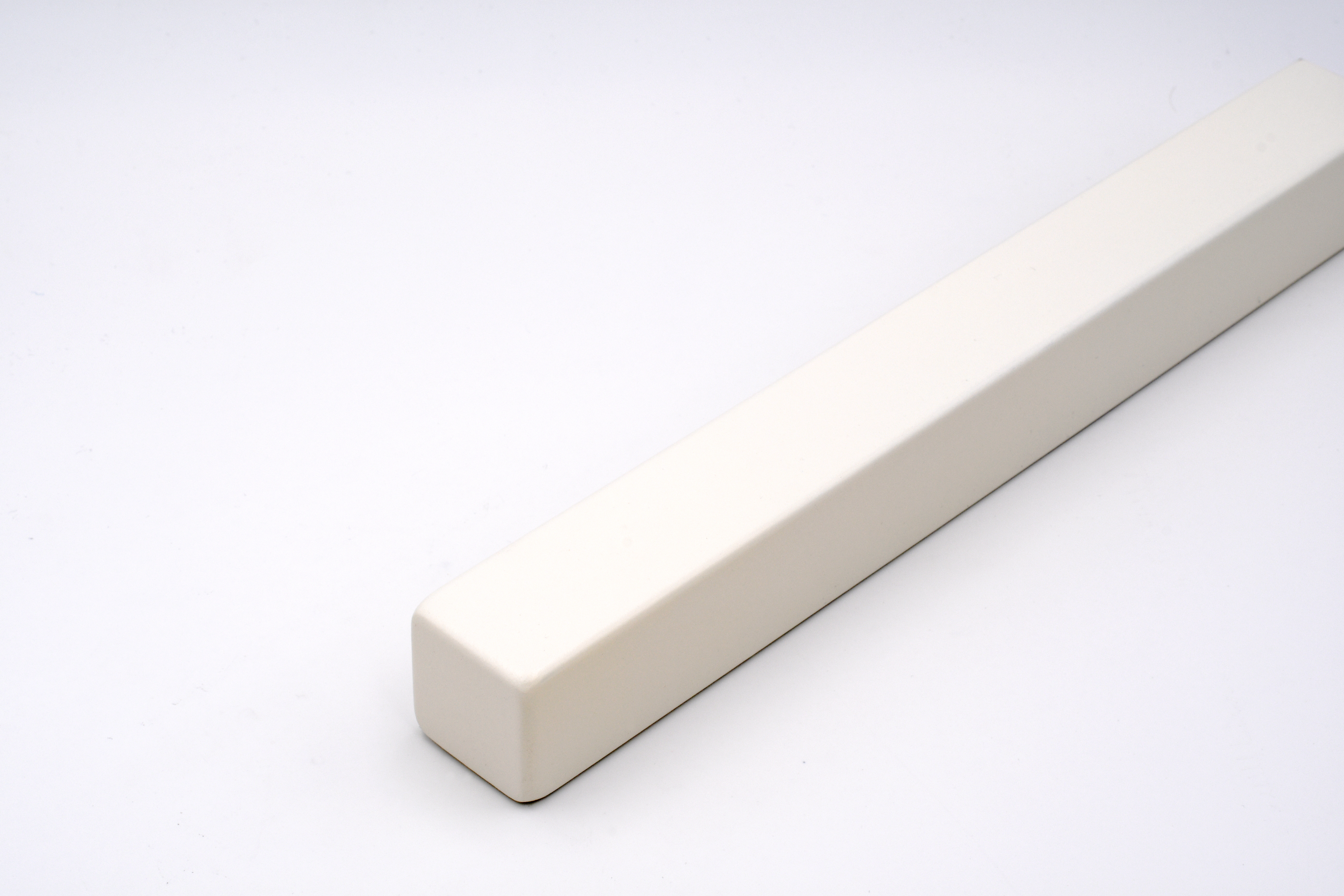 Corrimano verniciato bianco con profilo quadrato e spigoli leggermente arrotondati, adagiato in diagonale su sfondo bianco