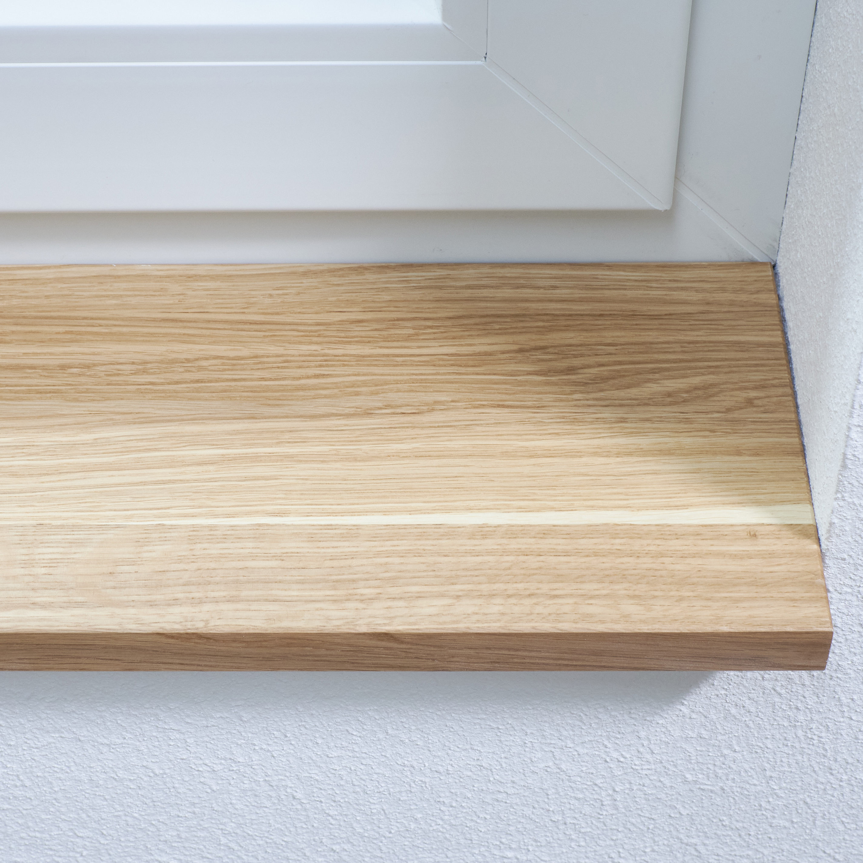 Davanzale in rovere massello naturale, montato sotto un telaio di finestra bianco, primo piano della venatura