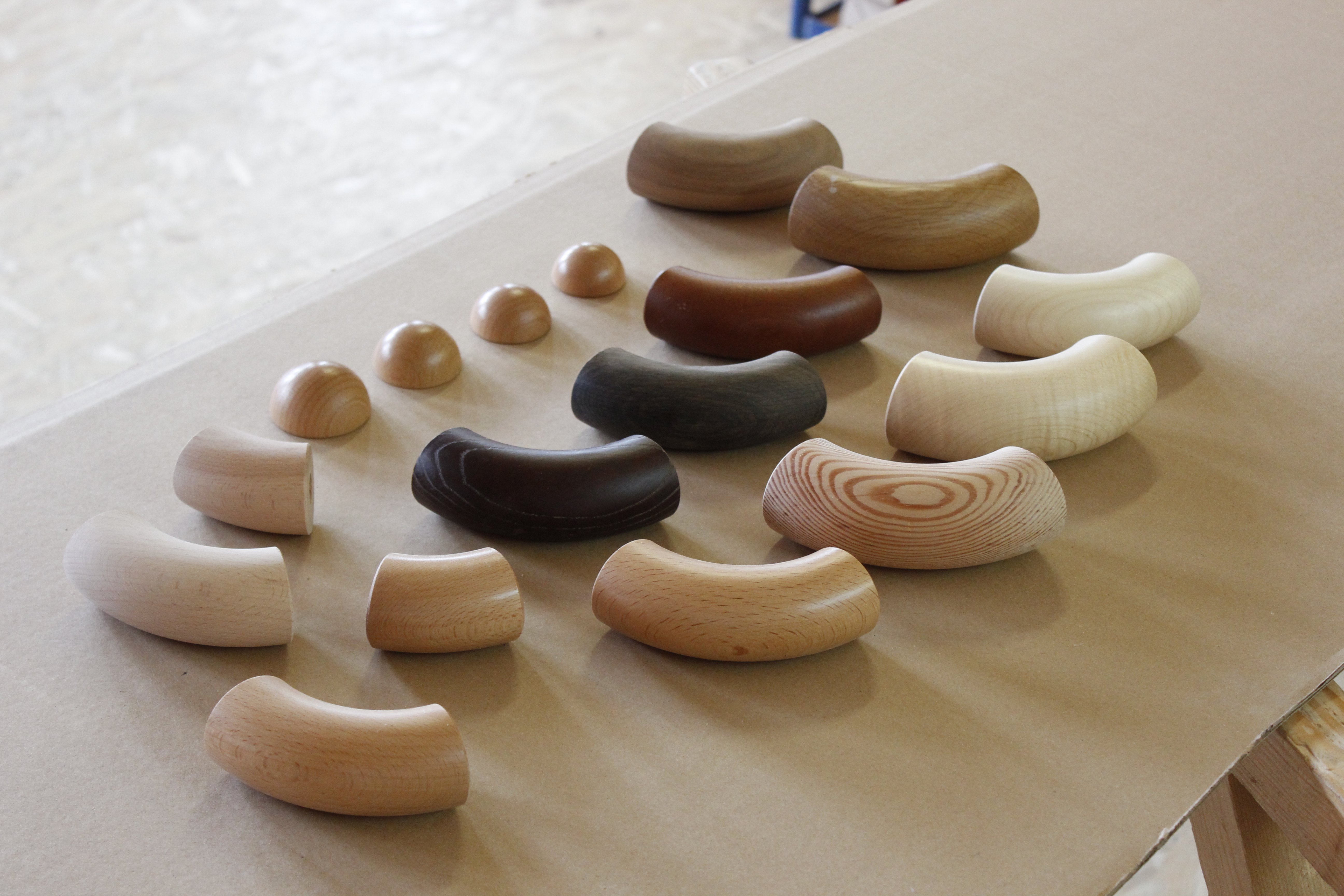 Accessori per corrimano in legno: curve e tappi terminali semisferici in diverse essenze su carta nel laboratorio