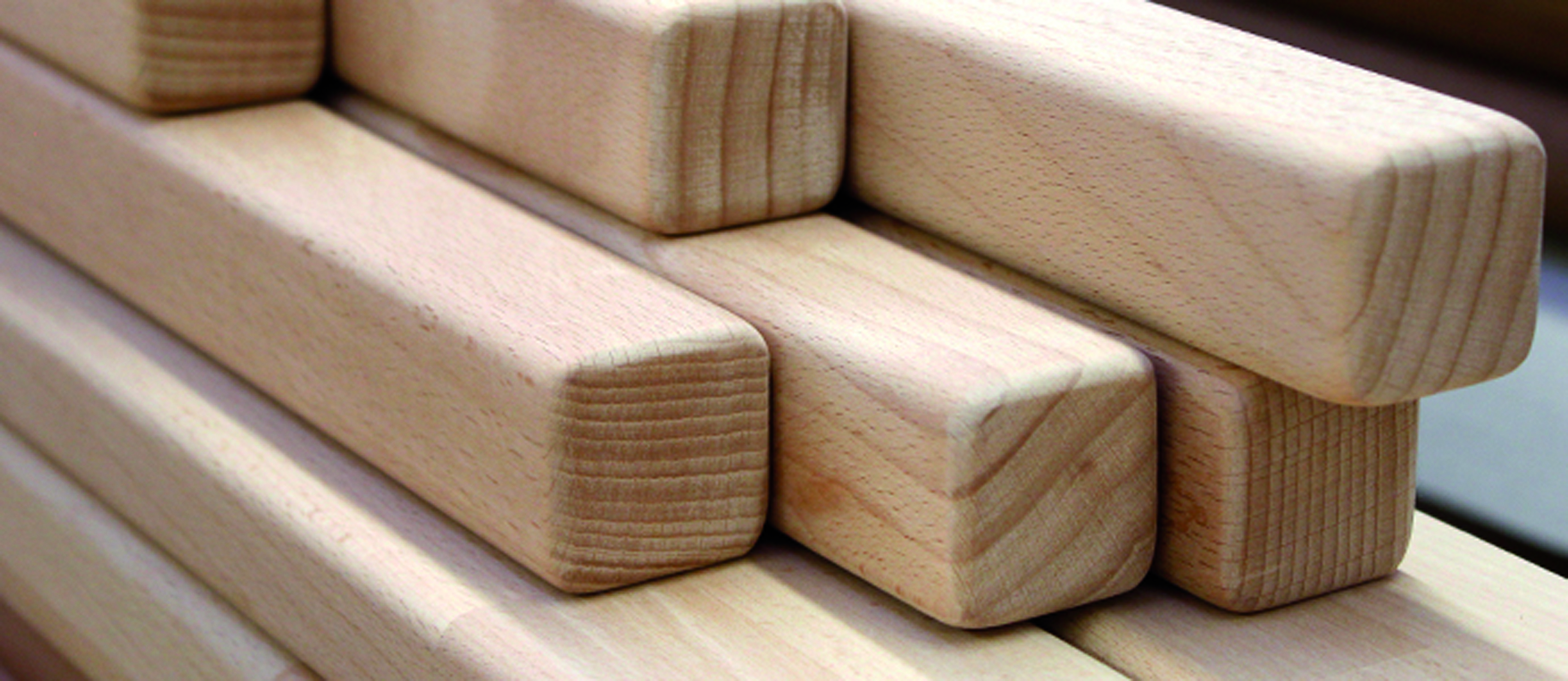 Corrimano in legno quadrati impilati, legno chiaro con bordi smussati e testate visibili, primo piano