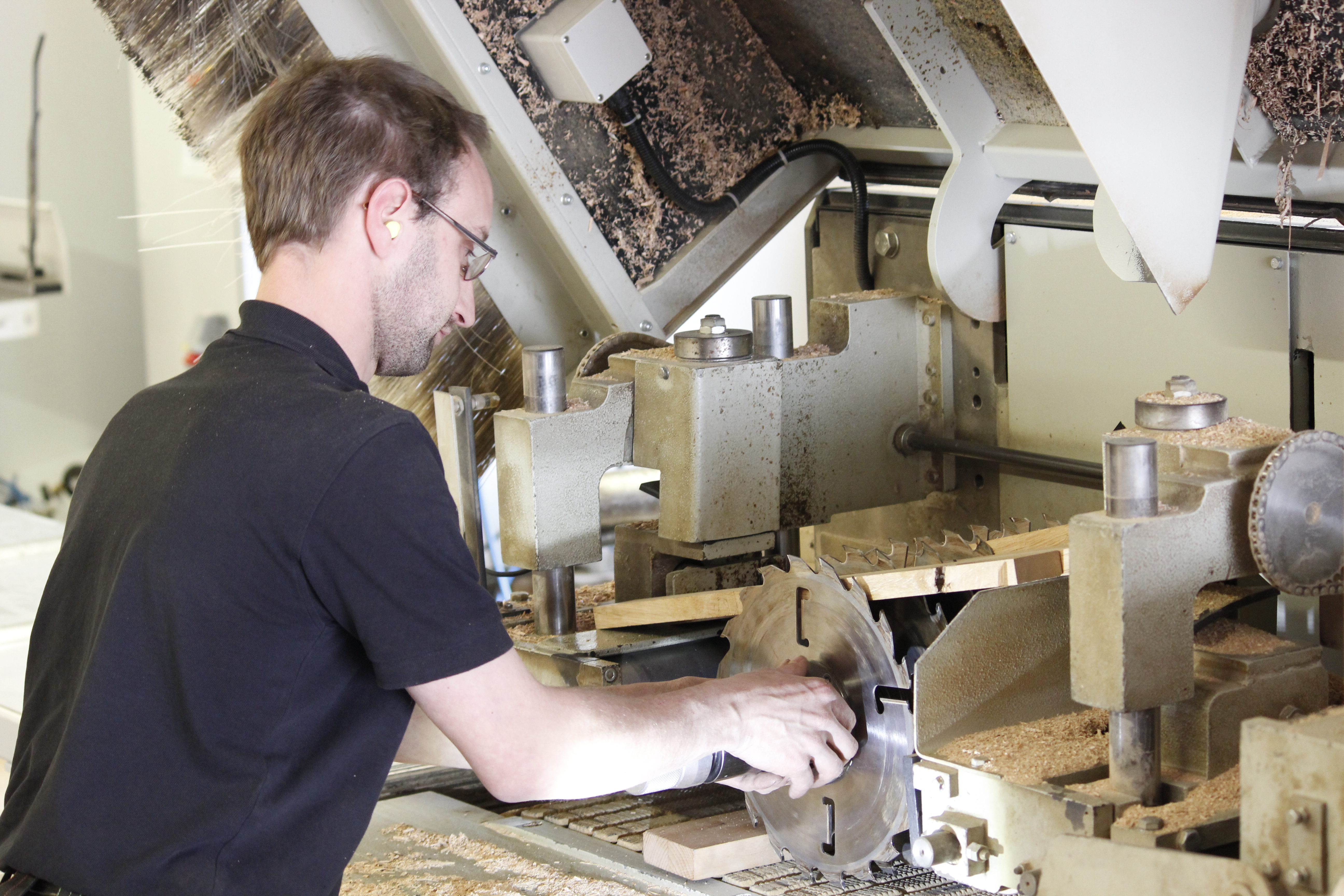Falegname a una piallatrice in officina durante la lavorazione del legno massello, trucioli sulla macchina