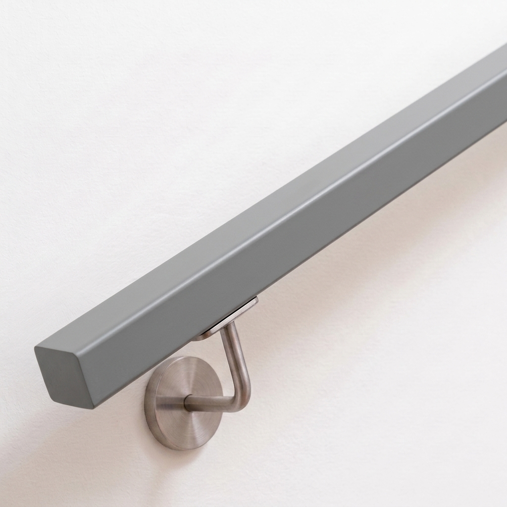 Corrimano quadrato in faggio verniciato grigio su parete bianca con supporto a parete inox, estremità diritta, vista obliqua