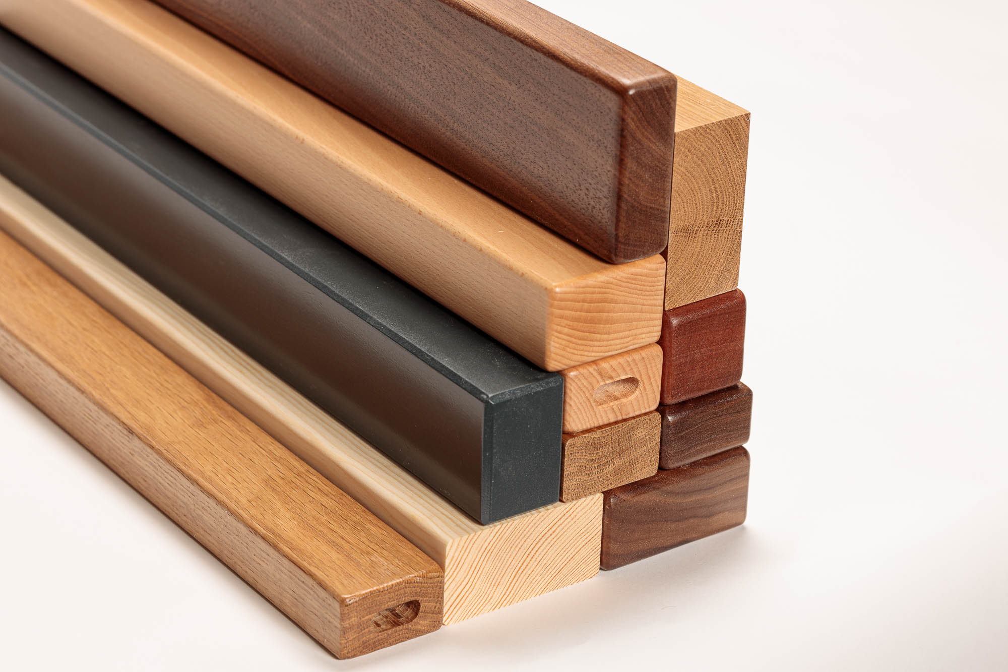 Corrimano in legno rettangolari in diverse essenze e colori impilati, profili chiari, scuri e verniciati neri