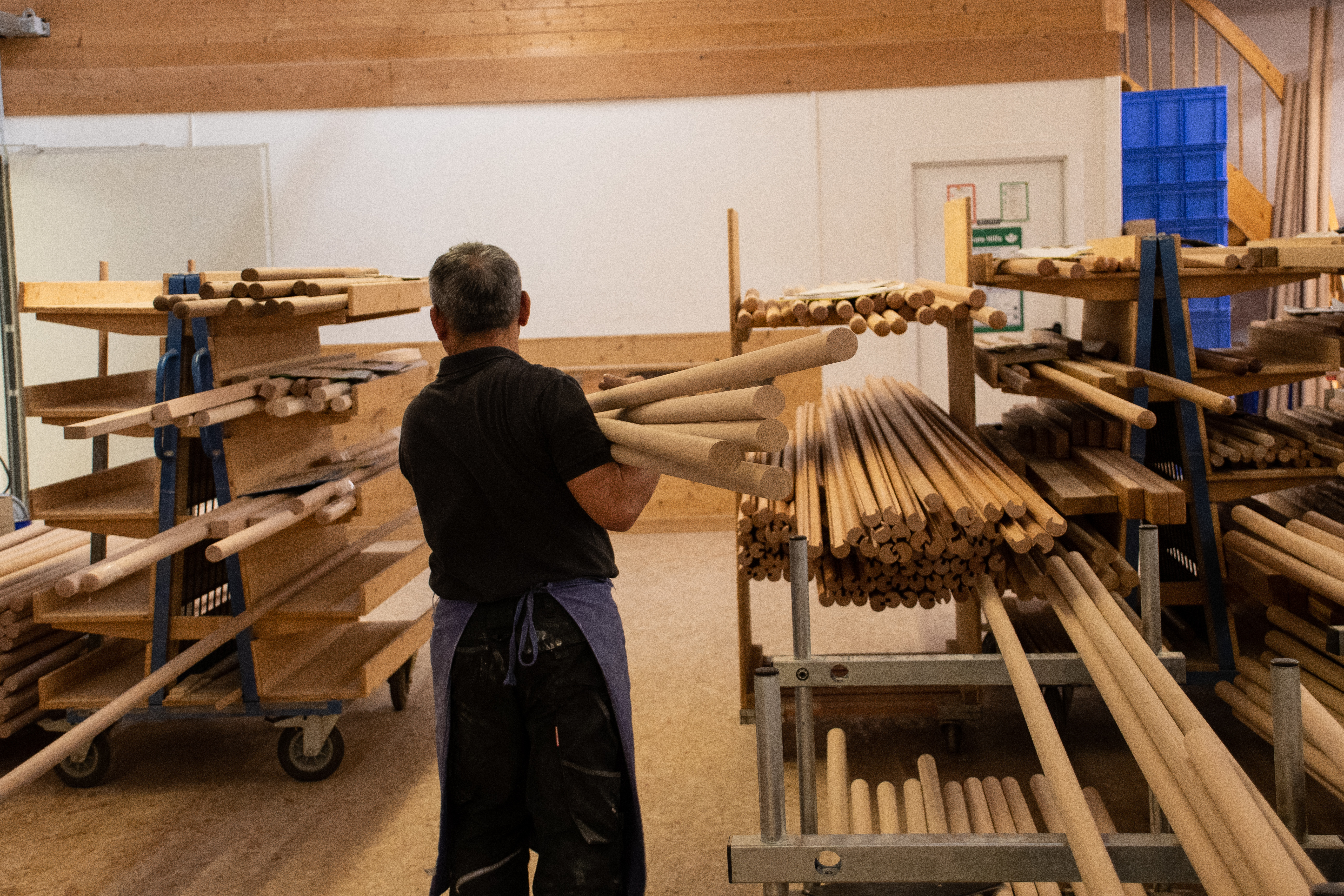 Tondini in legno sullo scaffale dell'officina, addetto sistema le aste di legno in torneria, molti diametri