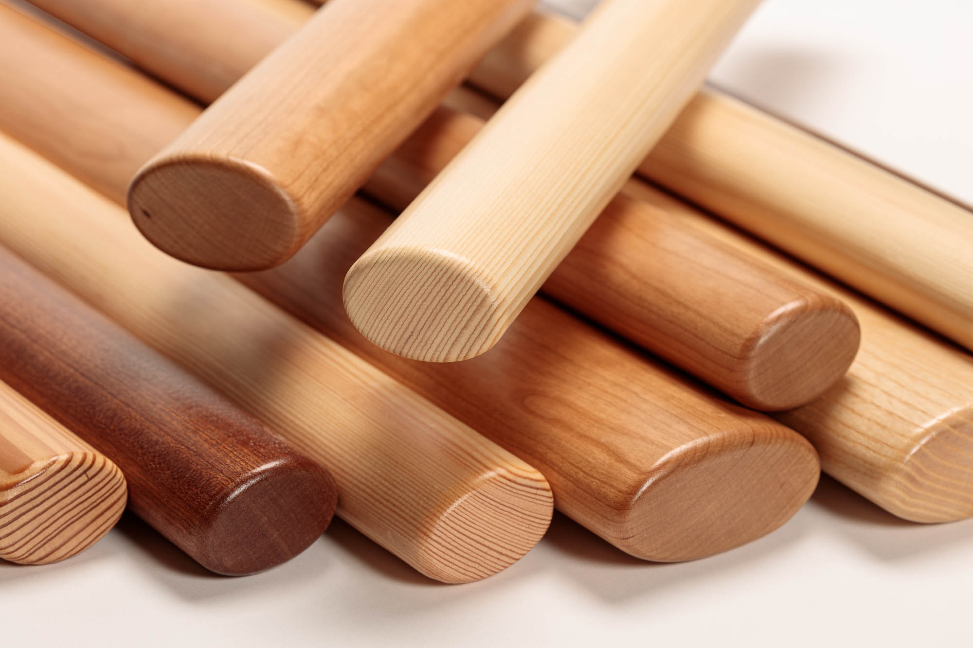 Corrimano in legno ovali in diverse essenze impilati, estremità arrotondate con venatura visibile, primo piano