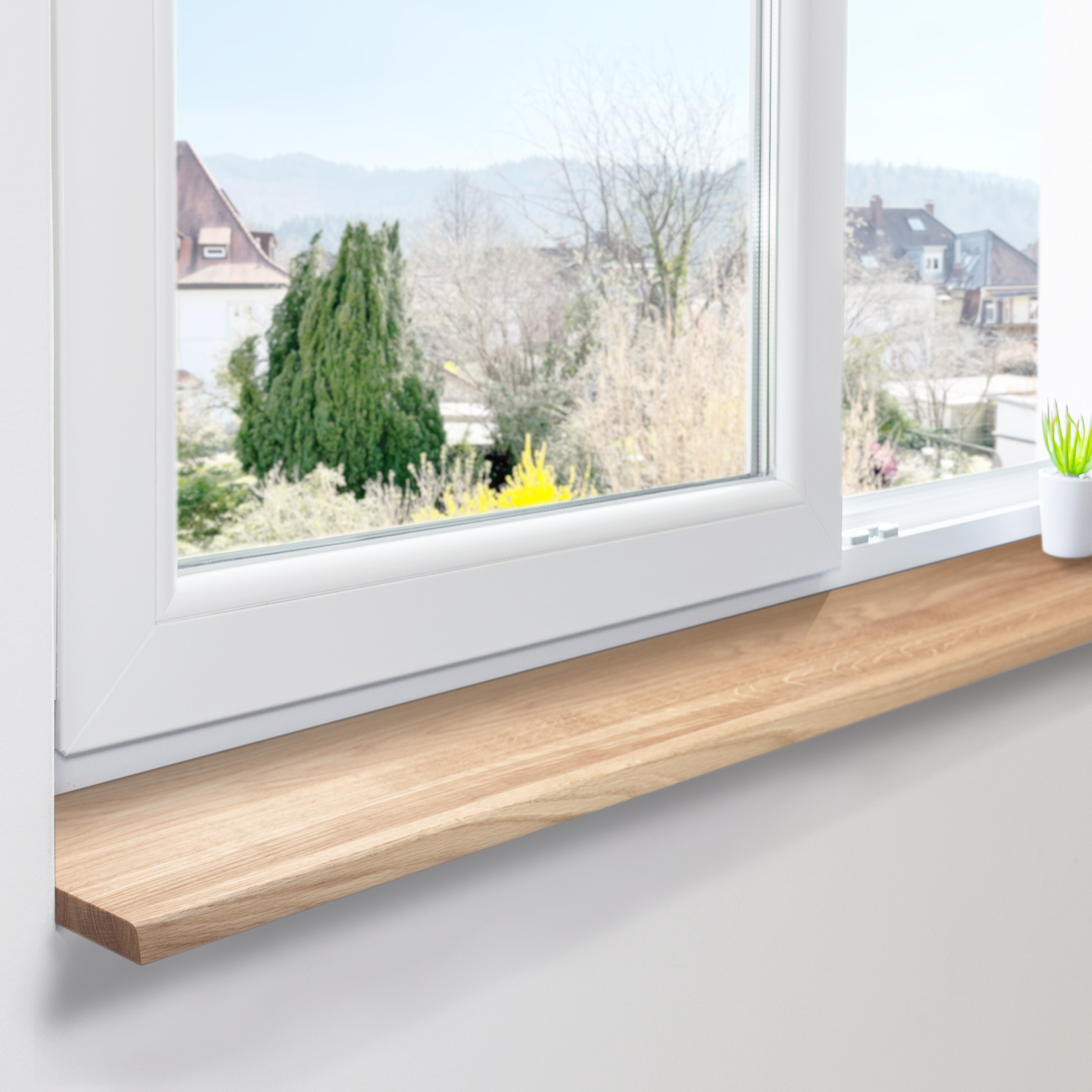 Davanzale in rovere naturale montato su finestra bianca in PVC, lamelle continue, vista su case e alberi