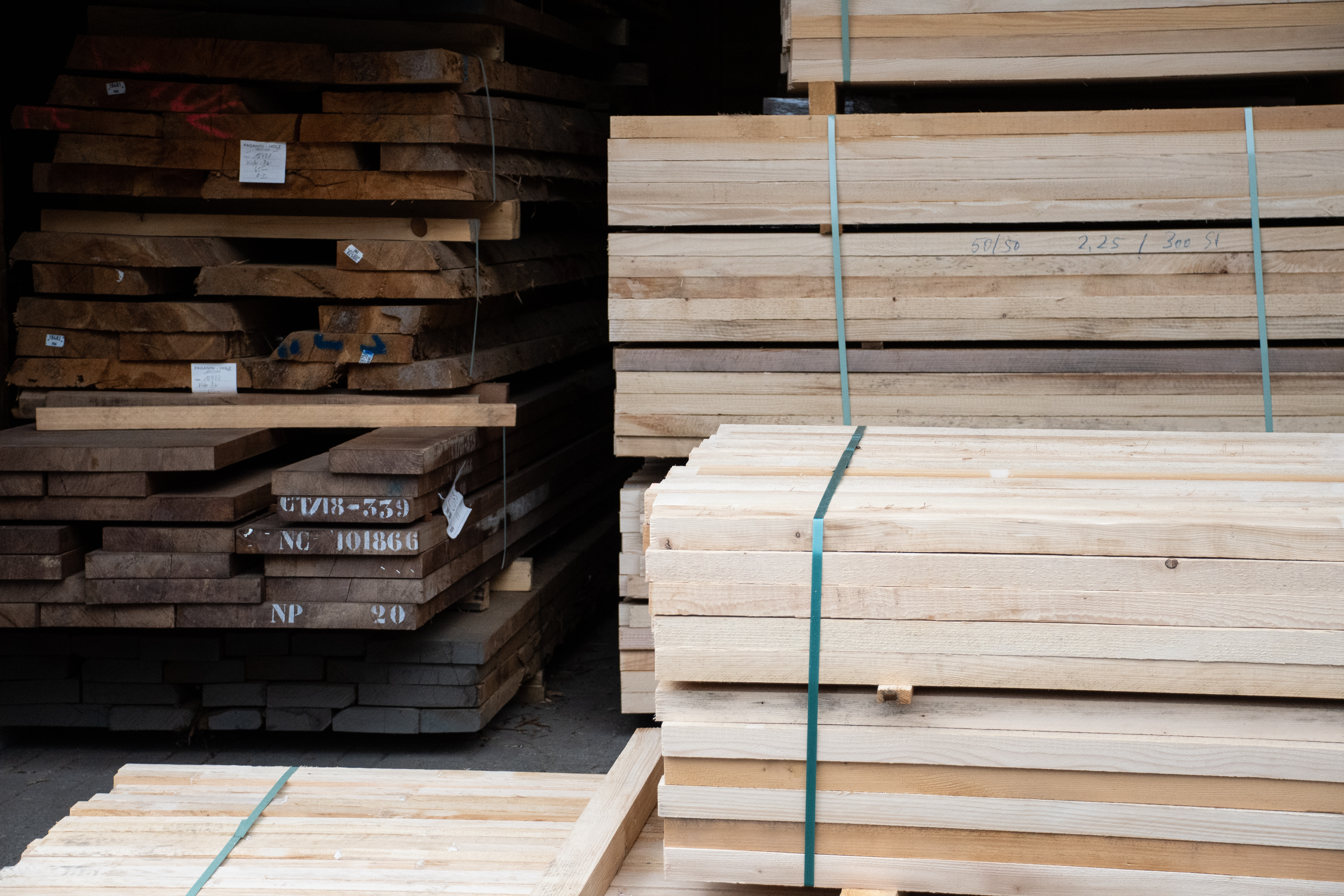 Magazzino del legno con tavoloni di legno massello accatastati e tavole chiare in fasci, materia prima per corrimano in legno